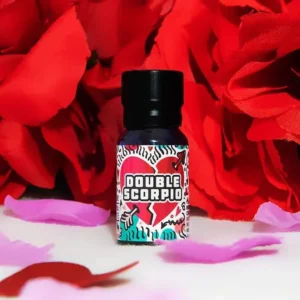A small bottle labeled "double scorpio love potion - 10ml" stands upright against a backdrop of vibrant red flowers with a few pink petals scattered around. This 10ml bottle features a colorful, abstract design on its label, adding an enchanting touch to the scene.